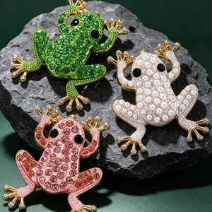 Kreative Frosch-Ohrstecker mit Strass und Perlen auf einer strukturierten Steinfläche