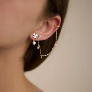 Détail de boucles d'oreilles papillon en or 18k avec chaîne à pompons et manchette