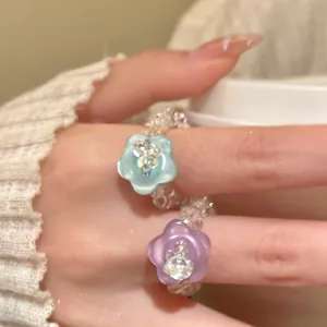 Detailansicht von farbenfrohen Kristallblumen-Perlenringen an der Hand eines Models.