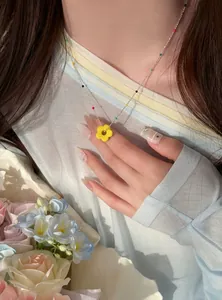 Detail einer bunten Dopamin-Perlenkette mit gelber Blume an einem Modell.