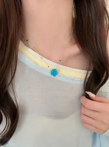 Nahaufnahme einer bunten Blumen-Perlenkette mit einem blauen Anhänger an einem Model
