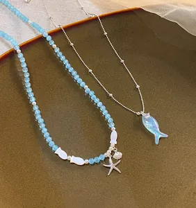 Delicate ocean style blue beaded necklace featuring starfish and iridescent fish pendants
