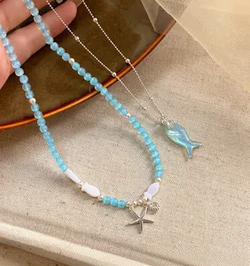 Detail of blue beaded necklace and silver chain with starfish and fish charms.