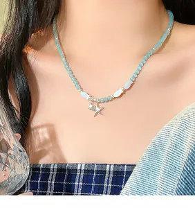 Detail shot of light blue beaded necklace featuring small fish and a silver starfish pendant