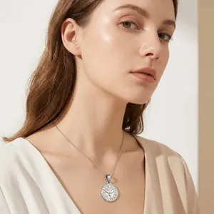 Macro view of a silver vintage round pendant necklace with a bird pattern on a model