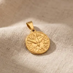 Close-up of gold-plated round pendant featuring flying bird motif and Latin engraving