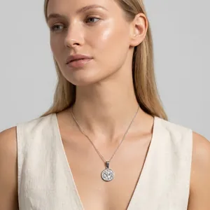 Close-up of a vintage silver-tone round pendant necklace with a flying bird motif on a model