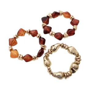 Set aus drei klobigen, unregelmäßigen Perlenarmbändern mit bernsteinfarbenem Acryl und Gold.