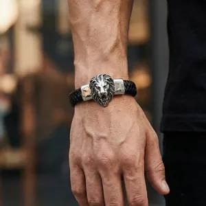 Gros plan d'un bracelet pour homme en cuir tressé noir avec une tête de lion en argent