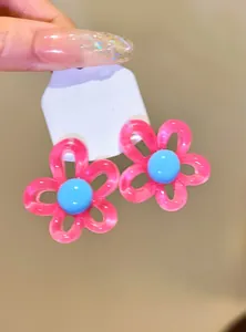 Detail view of cute pink and blue dopamine-style flower stud earrings with glossy finish.