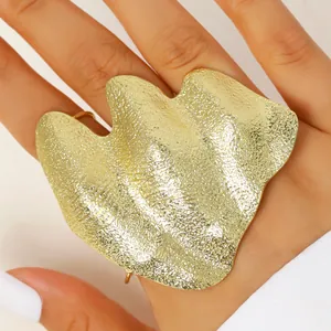 Detailed macro view of a large gold irregular wrinkled joint ring on a model's hand.