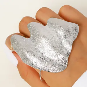 Detail view of artistic irregular silver knuckle ring featuring a pleated metallic texture