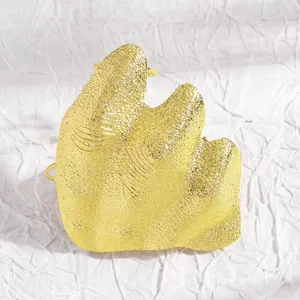 Detailed view of an artistic irregular pleated gold joint ring with granular texture