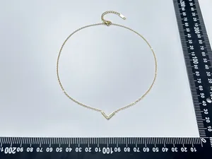 Detail of V-shaped gold necklace pendant with pavé diamonds and measurement scale