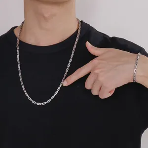 Detailweergave van minimalistische zilveren schakelketting en armbandset voor heren