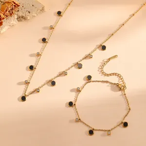 Close-up of gold stainless steel necklace and bracelet set with black disc pendants