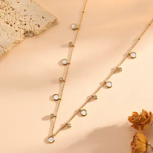 Close-up detail of a French style stainless steel necklace with round shell and rhinestone charms.