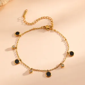 Detailed shot of gold-plated titanium steel bracelet with black discs and rhinestones.