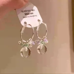 Detailed close-up of handmade silver hoop earrings with clear crystal beads.