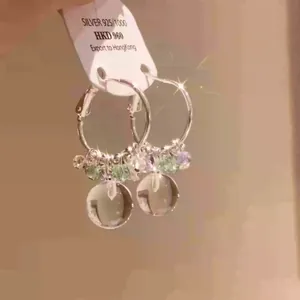Detailed macro view of forest style crystal bead hoop earrings with transparent round pendants