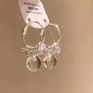 Close-up of forest style hoop earrings with purple beads and clear crystal ball pendants.
