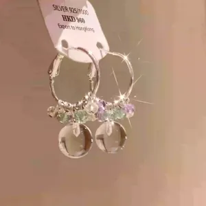 Detailed view of silver hoop earrings with crystal beads and glass ball pendants