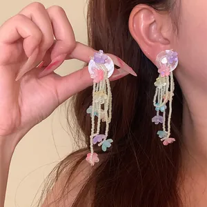 Close-up view of elegant colorful floral tassel beaded earrings with shell disc base
