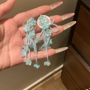 Detailed handheld shot of light blue floral beaded tassel earrings for beach vacations