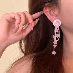 Detailed macro view of pink flower beads and elegant tassel chains on a dangling earring.