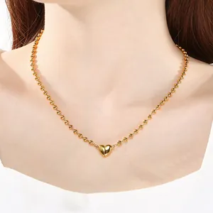 Dettaglio di una collana a sfere in oro e acciaio con chiusura magnetica a cuore.