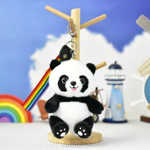Gros plan d'un joli porte-clés panda en peluche avec sangle arc-en-ciel sur un support.