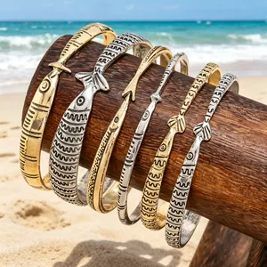 Detail van een visvormige armbandset in goud- en zilverkleur op houten strandstand