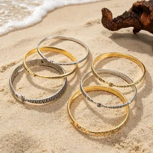 Detail van boheemse goud en zilveren armbanden met geometrische patronen op strandzand