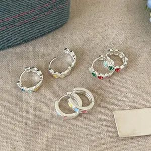 Detailed macro view of colorful heart and smiley face hoop earrings on beige linen cloth