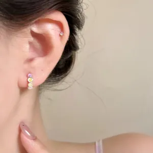 Close-up view of a woman wearing colorful smiley face hoop earrings with sweet design