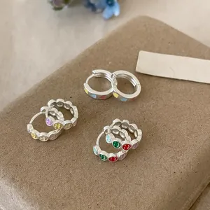 Detailed macro shot of colorful enamel heart and smiley face silver hoop earrings