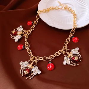 Detailed view of vintage gold chain necklace with enamel insect and crystal charms