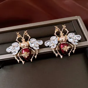 Close-up of vintage insect earrings with red enamel and clear crystals