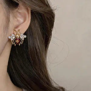 Vintage insect bee stud earring with crystal wings and red enamel finish on ear model