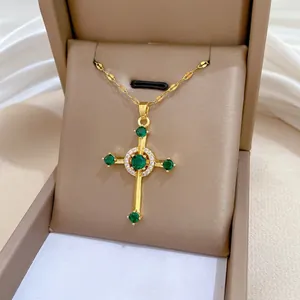 Detail of gold cross pendant with green emerald zircons and diamond halo in a gift box
