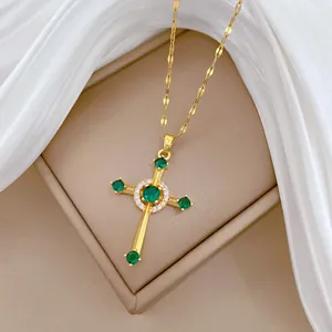 Detail of gold cross pendant with green emerald zircons on a luxury brown leather stand
