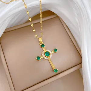 Macro shot of gold cross pendant featuring green zircon stones and white crystal halo