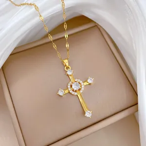 Close-up of gold cross necklace with sparkling zircon stones on white silk fabric