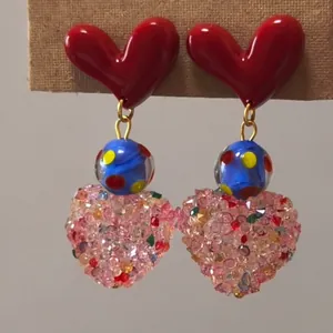 Detailed close-up of sweet and cool resin heart earrings with colorful crystal dangles.