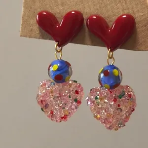 Close-up detail of red heart resin earrings with colorful beaded pendants