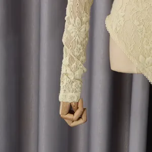 Détail du tissu en dentelle florale ajourée sur cette combinaison beige à manches longues