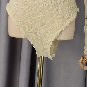 Détail d'un body en dentelle beige avec motifs floraux et fermeture par boutons-pression