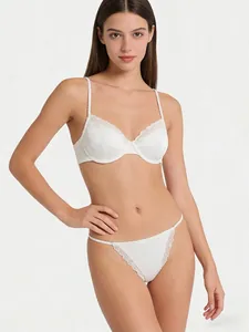 Close-up of white satin lingerie set featuring intricate eyelash lace and pleated straps
