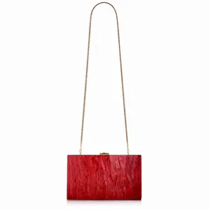 Dettaglio macro della borsa clutch in acrilico rosso marmo con catena dorata fine