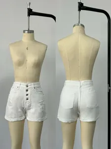 Detail of white high-waisted denim shorts with button fly, ripped effects and cuffed hems